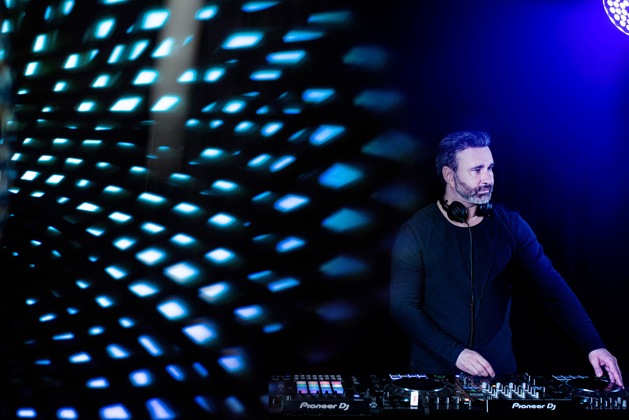 ritratto professionale di un Dj alla console con luci colorate, servisio fotografico di ritratto per artisti e musicisti realizzato in studio con gestione luci artificiali creative.