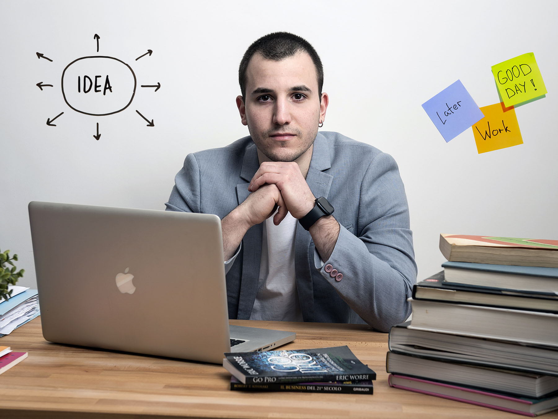 Ritratto professionale di un giovane creativo alla scrivania davanti al computer mac, con la scritta IDEA e appunti colorati sulla parete a muro di sfondo